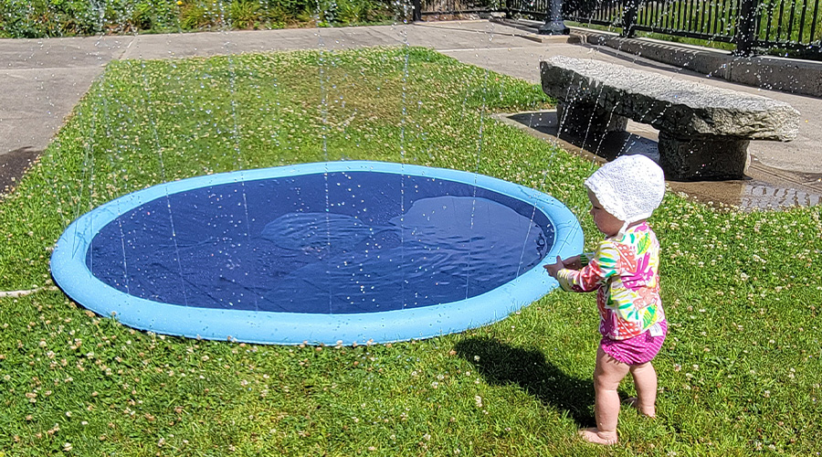 Child playing by inflatable pool/sprinkler