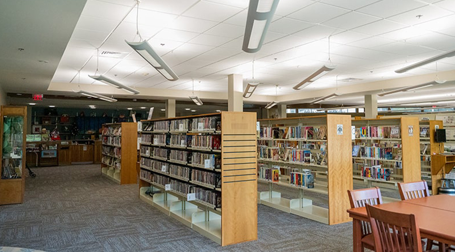Photograph of the Jesse M. Smith Memorial Library interior featuring full bookcases and bookshelves (wide shot)